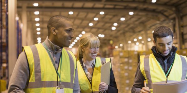 Smiling managers with paperwork in distribution warehouse